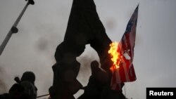 Para demonstran Iran di Teheran, Iran, membakar bendera AS dan Israel saat berkabung atas tewasnya Jenderal Qassem Soleimani, 4 Januari 2020. Soleimani, komandan pasukan elit Quds, tewas dalam serangan udara AS di Bandara Baghdad. (Foto: Nazanin Tabatabae)
