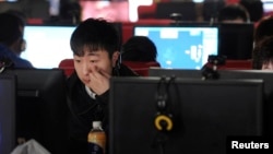 FILE - A man scratches his face as he uses a computer at an internet cafe in Hefei, Anhui province March 16, 2012. Foreign businesses operating in China fear new rules on online publication may mean further curbs, as groups from across politics, business and civil society try to understand the scope of the legislation. 