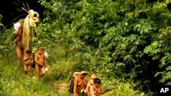 In this undated 2014 handout photo released by Brazil’s National Indian Foundation, FUNAI, members of the Korubo tribe walk along a path in the Javari Valley, in the northern state of Amazonas, Brazil. 