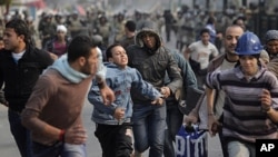 Egyptian protesters run as they are chased by army soldiers over the Asr el-Nile bridge leading out of Tahrir Square, in Cairo, Egypt, Saturday, Dec. 17, 2011.