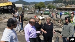 Chile's President Michelle Bachelet (2ndR) talks to residents in a destroyed area of Concepcion, some 100 km (62 miles) south of the epicenter of a huge 8.8-magnitude earthquake that rocked Chile on February 27, 2010.