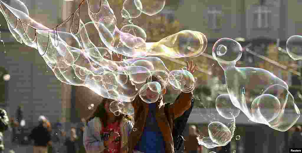 Children try to reach a big soap bubble blown at a square in front of the opera house in Zurich, Switzerland.