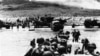 Kamioni-amfibije i pripadnici pešadije izlaze na obalu na početku invazije na Francusku, 6. juna 1944. 