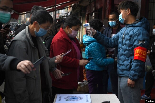 云南昆明民众戴着口罩拿着手机进行个人健康扫码方能进入超市购物。(2020年2月24日)