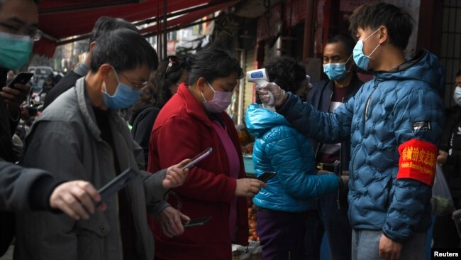 云南昆明民众戴着口罩拿着手机进行个人健康扫码方能进入超市购物。(2020年2月24日)