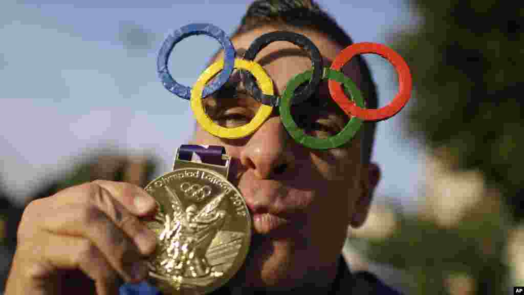 A man poses for a picture wearing Olympic rings glasses and kissing a medal before entering the Maracana Stadium ahead of the opening ceremony for the 2016 Summer Olympics in Rio de Janeiro, Brazil, Aug. 5, 2016. (AP Photo/Natacha Pisarenko)