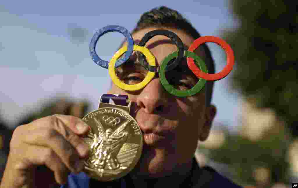 A man poses for a picture wearing Olympic rings glasses and kissing a medal before entering the Maracana Stadium ahead of the opening ceremony for the 2016 Summer Olympics in Rio de Janeiro, Brazil, Aug. 5, 2016.