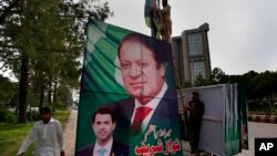 Pakistani workers install a huge billboard of deposed Prime Minister Nawaz Sharif on the planned route of his rally on a highway in Islamabad, Pakistan, Aug. 8, 2017.