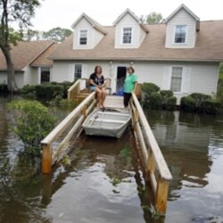 A family sitting in front of their flooded home after a storm surge on the Outer Banks in Kitty Hawk, North Carolina last month