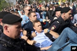 Russian police carrying struggling opposition leader Alexei Navalny, center, at a demonstration against President Vladimir Putin in Pushkin Square in Moscow, Russia, Saturday, May 5, 2018.
