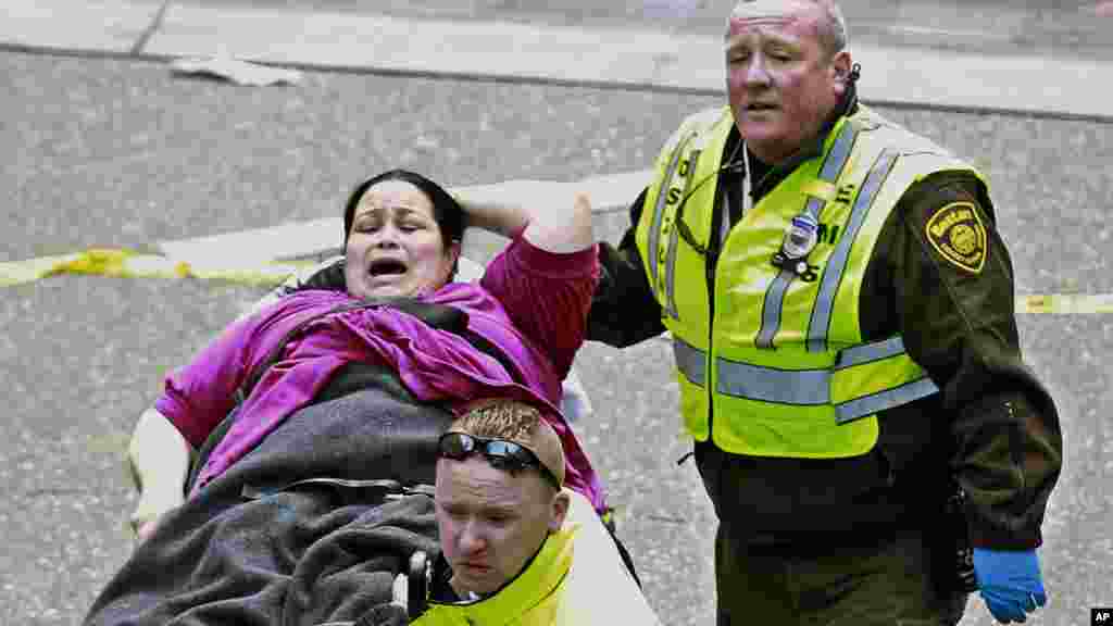 Medical workers aid a wounded woman at the finish line of the 2013 Boston Marathon following two explosions there, April 15, 2013.