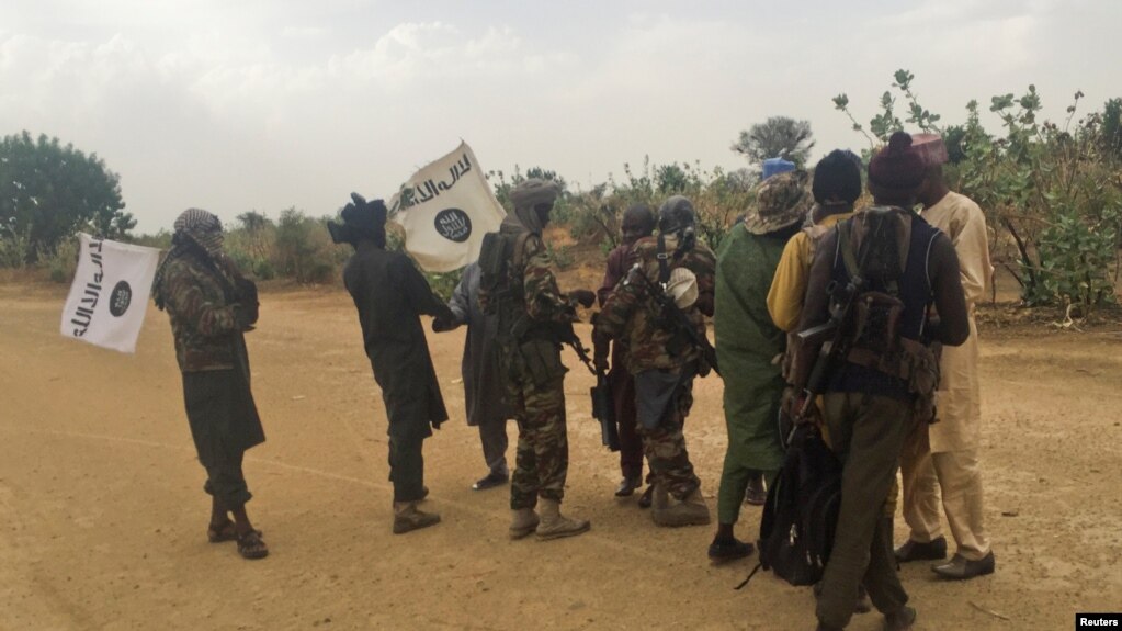 FILE - Boko Haram militants (in camouflage) embrace and shake hands with Boko Haram prisoners, released in exchange for a group of 82 Chibok girls, who were held captive for three years by Islamist militants, near Kumshe, Nigeria, May 6, 2017.