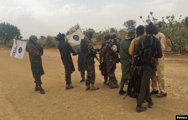 Boko Haram militants (in camouflage) embrace and shake hands with Boko Haram prisoners, released in exchange for a group of 82 Chibok girls, who were held captive for three years by the Islamist militant group, near Kumshe, Nigeria, May 6, 2017.