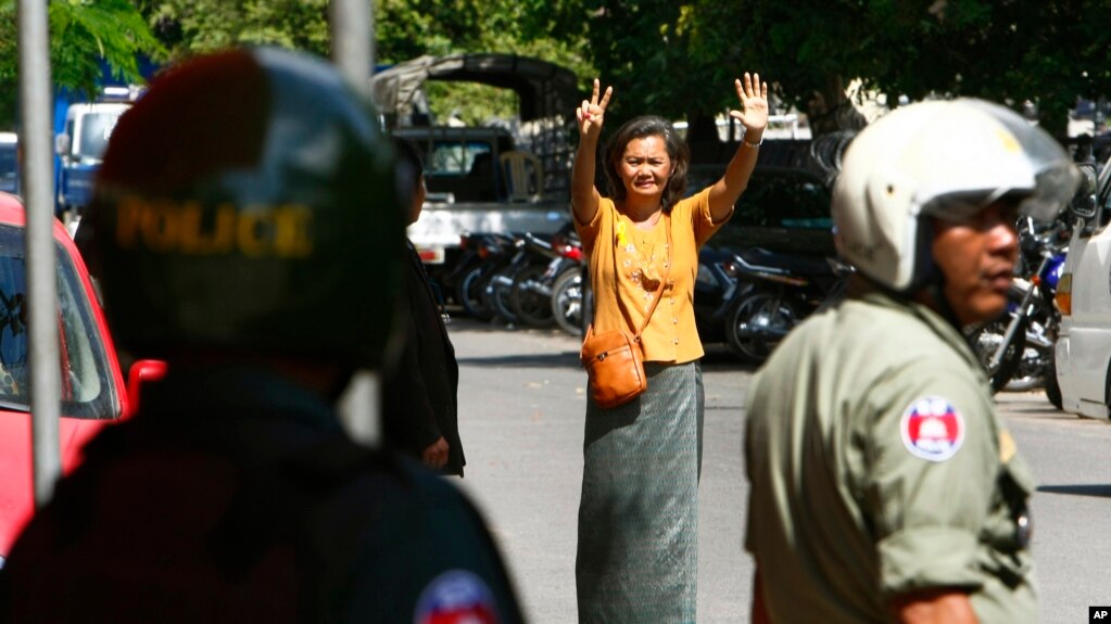 FILE PHOTO - A Cambodian lawmaker from the main opposition party of Cambodia National Rescue Party (CNRP) Mu Sochua, center, gestures to make the number seven, the party's ballot number, before being detained by authorities at Freedom Park, in Phnom Penh, Cambodia.