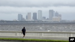 A resident walks along Bayshore Boulevard in between squalls blowing across the bay in Tampa, Florida, Monday, Aug. 27, 2012.