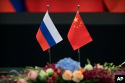 FILE - Russian, left, and Chinese flags sit on a table before a signing ceremony at the Great Hall of the People in Beijing, June 8, 2018.