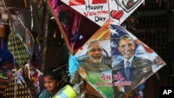 在印度海得拉巴的风筝节前夕，一名印度女孩站在一家店铺出售的画有印度总理莫迪和美国总统奥巴马头像的风筝边。（2015年1月12日）