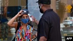 A person gets a temperature check before entering an Apple store on June 22, 2020 in the Brooklyn Borough of New York City. (Angela Weiss / AFP)