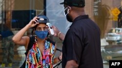 A person gets a temperature check before entering an Apple store on June 22, 2020 in the Brooklyn Borough of New York City. (Angela Weiss / AFP)