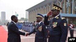 Le président ivoirien Alassane Ouattara, à gauche, salut le commandant en chef de la gendarmerie nationale ivoirienne, Nicolas Kouadio Kouakou, accompagné du directeur général de la police ivoirienne, Youssouf Kouyate, à droite, à Abidjan, le 4 janvier201