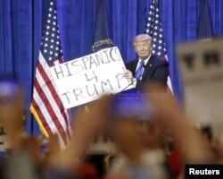 FILE - Republican U.S. presidential candidate Donald Trump holds up a sign from the audience as he speaks to supporters at a Super Tuesday campaign rally in Louisville, Kentucky, March 1, 2016.