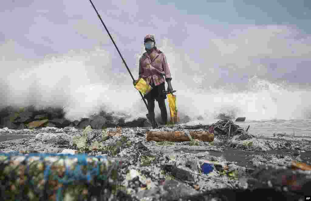 A Sri Lankan man fishes on a polluted beach filled with plastic pellets washed ashore from the fire-damaged container ship MV X-Press Pearl in Kapungoda, on the outskirts of Colombo, Sri Lanka.