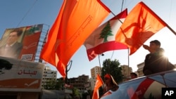 FILE - Lebanese supporters of the Free Patriotic Movement of Christian leader Michel Aoun wave the Lebanese and the party's orange flags as they ride their cars in the Christian stronghold of Metn north of Beirut, Lebanon, June 5, 2009.