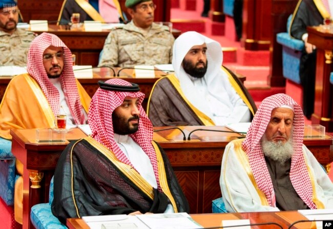 Photo provided by the Saudi Press Agency, SPA, Crown Prince Mohammed bin Salman (front left) seated next to the country’s most senior cleric, listens to Saudi King Salman give his annual policy speech in the ornate hall of the consultative Shura Council,