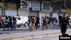 Supporters of Iraqi Shiite armed groups run from security forces after clashes during a protest against the election results in Baghdad, Iraq, Nov. 5, 2021.