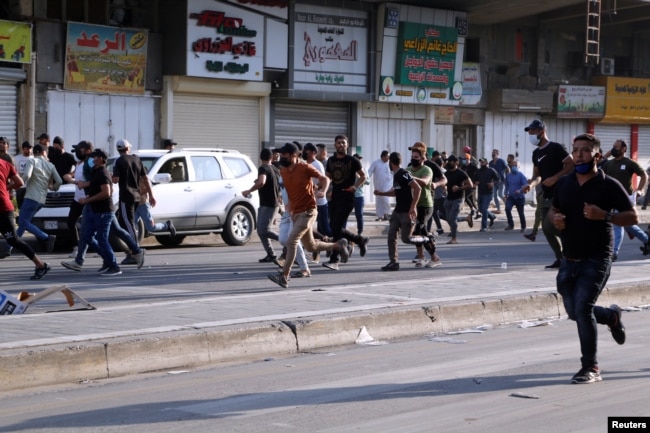 FILE - Supporters of Iraqi Shiite armed groups run from security forces after clashes during a protest against the election results in Baghdad, Iraq, Nov. 5, 2021.