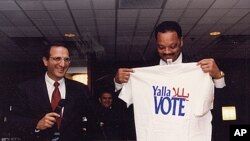 James Zogby and Jesse Jackson holding a T-shirt bearing the Arab American Institute's get-out-the-vote logo. 'Yalla' means 'Come on,' in Arabic.