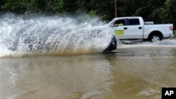 Motorists drive through a flooded street in Leonardtown, Maryland., after Hurricane Irene, Sunday, Aug. 28, 2011