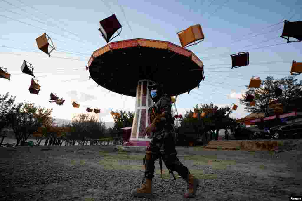 A Taliban fighter walks past a ride as he takes a day off to visit the amusement park at Kabul&#39;s Qargha reservoir in the outskirts of Kabul, Afghanistan Oct. 29, 2021.