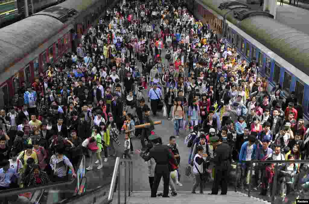 Paramilitary policemen direct passengers at a railway station during the traffic rush of the May Day holiday in Hefei, Anhui province, China.