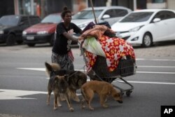 Cristiane, a 40-year-old homeless woman, walks with her dogs Luis, Spike, Poseidon and Perola, near Copacabana beach, Rio de Janeiro, Brazil, Dec. 9, 2017.