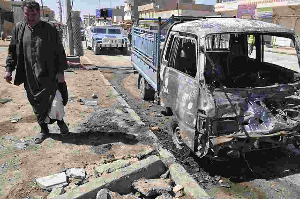 Seorang pria menghampiri mobil yang rusak dihantam bom di Ramadi (AP).