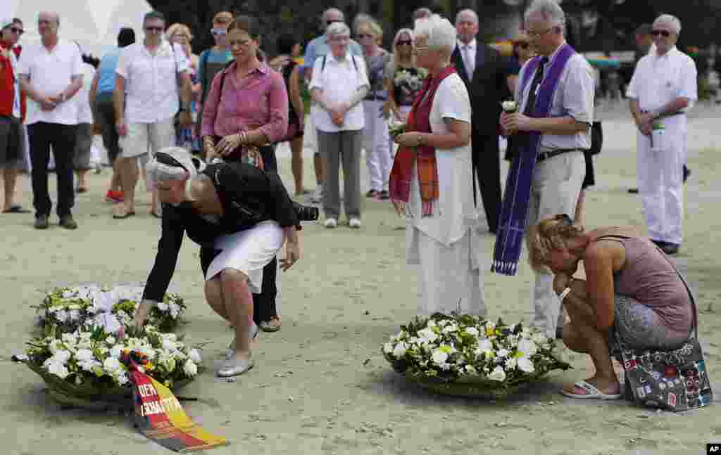 Relatives of victims of the Asian tsunami lay white roses on the beach during a commemoration and religious ceremony for German, Austrian and Swiss victims in Khao Lak, Thailand, Friday, Dec. 26, 2014. 