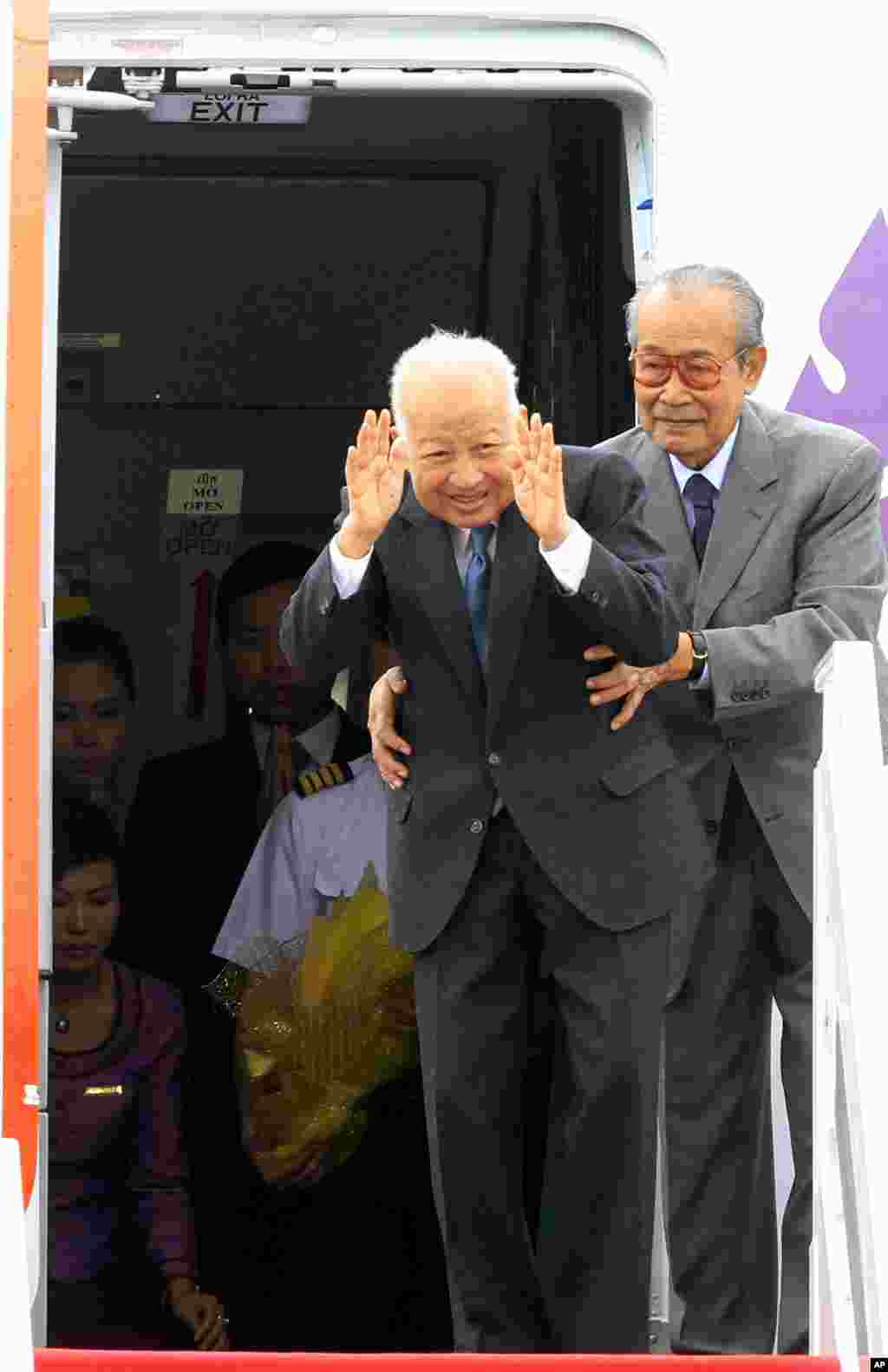 Kong Sam Ol, right, holds King Sihanouk to help him greet people before boarding an airplane at Phnom Penh international airport, Cambodia, January 19, 2012.