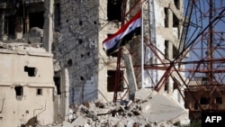 The Syrian national flag rises in the midst of damaged buildings in Daraa-al-Balad, an opposition-held part of the southern city of Daraa, on July 12, 2018. 