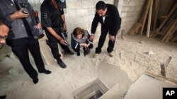 In this photo provided by Mexico's attorney general, authorities inspect the exit of the tunnel they claim was used by drug lord Joaquin "El Chapo" Guzman to break out of the Altiplano maximum security prison in Almoloya, west of Mexico City, July 12, 201