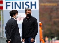 Kepala Organisasi Atletik Dunia Sebastian Coe (kanan), mengenakan masker, menyaksikan Hokkaido-Sapporo Marathon Festival 2021, acara pengujian lomba maraton Olimpiade Tokyo 2020, 4 Mei 2021. (REUTERS)