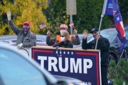 Sekelompok pendukung Presiden Donald Trump mengibarkan bendera dan memegang tanda, Senin, 2 November 2020, di dekat jalan raya di jalan raya di Seattle, sehari sebelum hari pemilihan. (Foto: AP/Ted S. Warren)