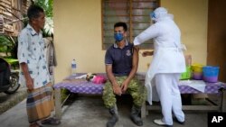 A nurse administers a Pfizer COVID-19 vaccine to a farmer outside his home in rural Sabab Bernam, central Selangor state, Malaysia, Tuesday, July 13, 2021. (AP Photo/Vincent Thian)