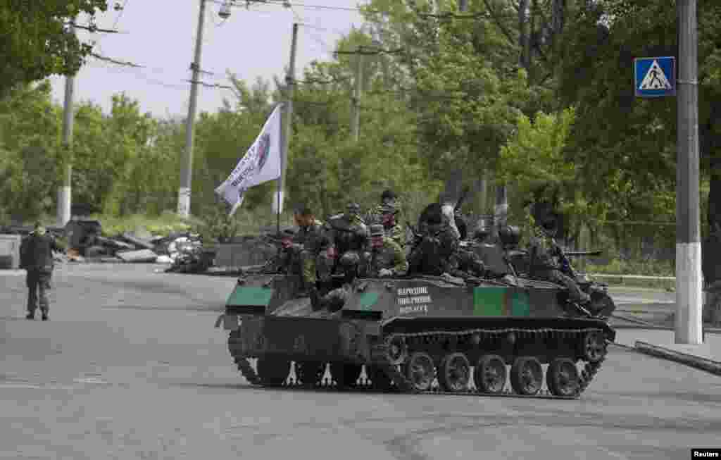 Pro-Russian armed men ride on top of an armored personnel carrier near the town of Slovyansk, May 5, 2014.