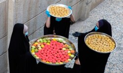 Perempuan Irak membawa kue untuk perayaan Idulfitri di Basra, Irak, Jumat, 22 Mei 2020. (AP Photo / Nabil al-Jurani)