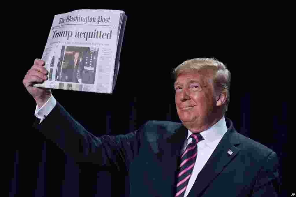 President Donald Trump holds up a newspaper with the headline that reads &quot;Trump acquitted&quot; during the 68th annual National Prayer Breakfast, at the Washington Hilton in Washington, D.C.