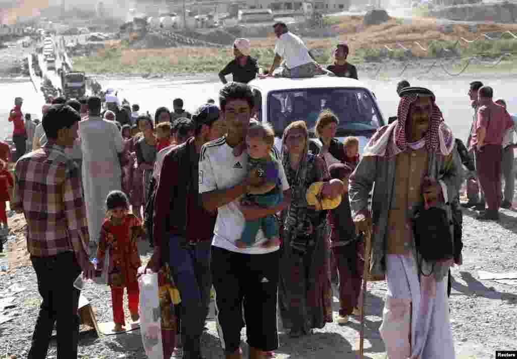 Displaced people from the minority Yazidi sect, fleeing violence in the Iraqi town of Sinjar, re-enter Iraq from Syria at the Iraqi-Syrian border crossing in Fishkhabour, Dohuk province, Aug. 10, 2014.