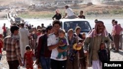 Displaced people from the minority Yazidi sect, fleeing violence in the Iraqi town of Sinjar, re-enter Iraq from Syria at the Iraqi-Syrian border crossing in Fishkhabour, Dohuk province, Aug. 10, 2014.