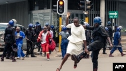 FILE: An anti-riot police man in Zimbabwe tackles a woman with his boot as they dispersed a crowd gathered to hear an address by leader of the MDC (Movement for Democratic Change) Alliance, Nelson Chamisa at Morgan Tsvangirai House, the party headquarters, in H