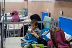 FILE - A mother gives milk to her two-year-old son as he undergoes treatment in the malnutrition ward of the Indira Gandhi Children's Hospital in Kabul, Afghanistan, Dec. 8, 2021.